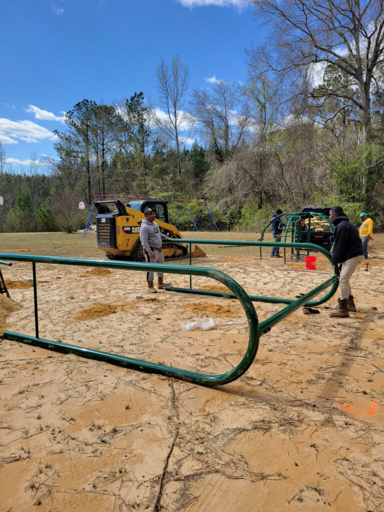 A playground swing set lies on the ground, about to be installed.